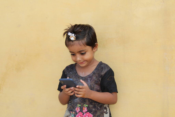 Hoş Asyalı çocuk gülümseyerek cep telefonunu izliyor. - Fotoğraf, Görsel