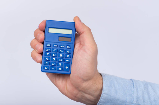 Mannelijke hand houden calculator op witte achtergrond. Financiële activiteit. Boekhouding. Sluiten.. - Foto, afbeelding