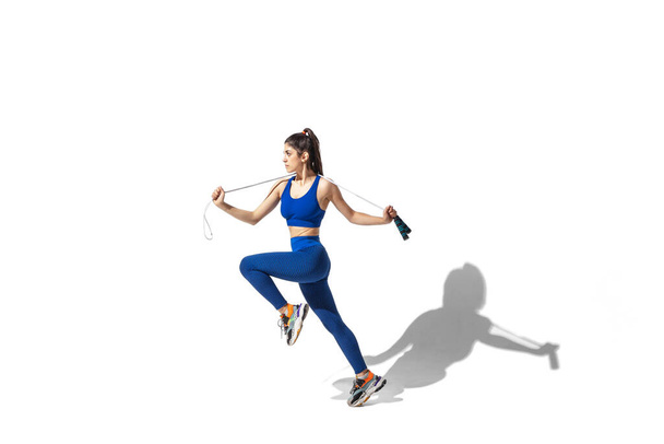 Beautiful young female athlete practicing on white studio background with shadows - Foto, immagini