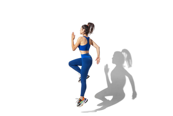 Beautiful young female athlete practicing on white studio background with shadows - Foto, imagen