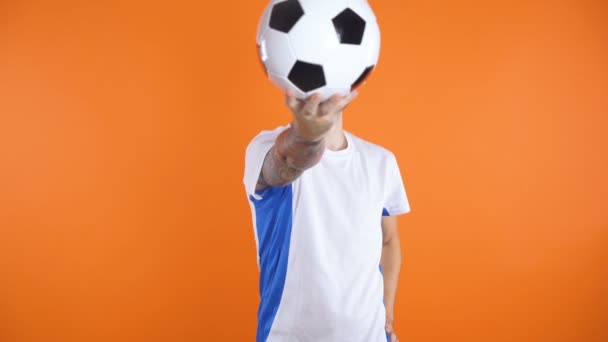 Confident looking Football fan or player posing with football in front of face, then holding it under arm - Filmagem, Vídeo