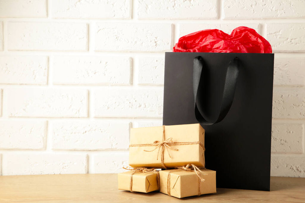 Black shopping bag with gift on light background. Black friday. Top view - Foto, Imagem