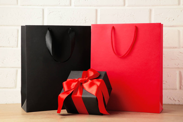 Black and red shopping bags with gift on light background. Black friday. Top view - Photo, image