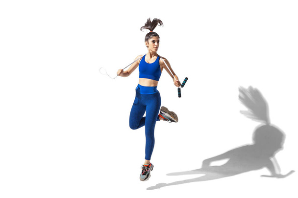 Beautiful young female athlete practicing on white studio background with shadows - Φωτογραφία, εικόνα
