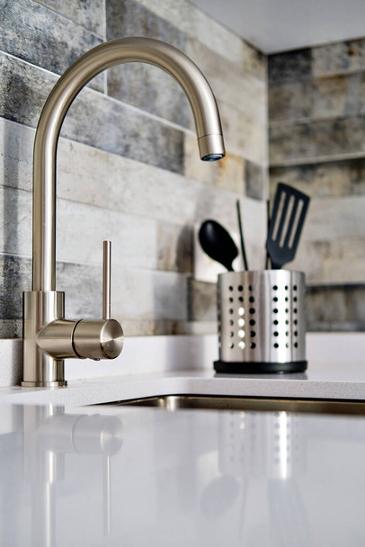Faucet and sink on tiled wall background in modern domestic kitchen - 写真・画像