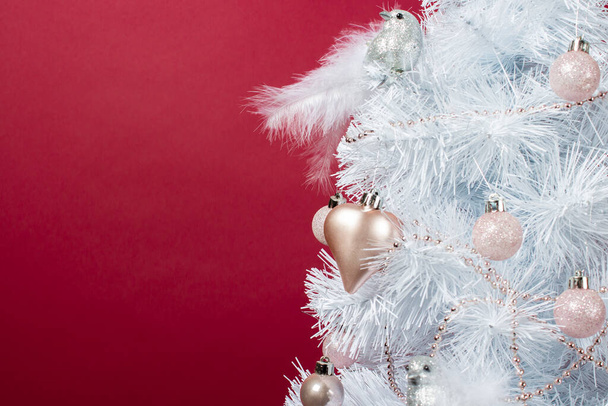 Witte boom versierd met decoratief speelgoed, ballen, hart en decoratieve zilveren vogel op een bordeaux achtergrond. Lege ruimte voor tekst. Winterfeest, Nieuwjaar, Kerstmis. Kerst boom close-up. - Foto, afbeelding