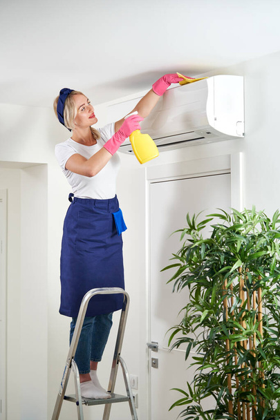 Nő légkondit tisztít ronggyal. Takarítási szolgáltatás vagy háziasszony koncepció - Fotó, kép