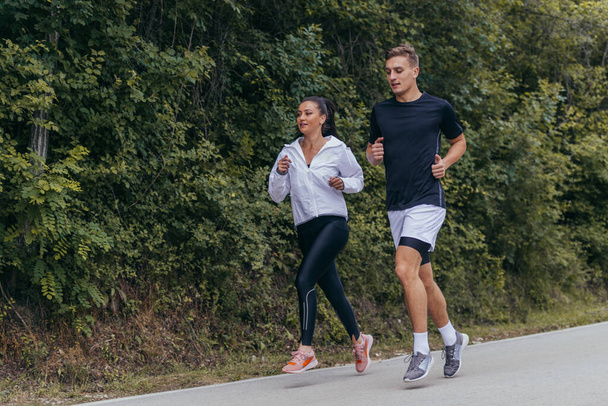 Athletic couple running on a street next to each other. Nature,fit and healthy concept. - Fotoğraf, Görsel