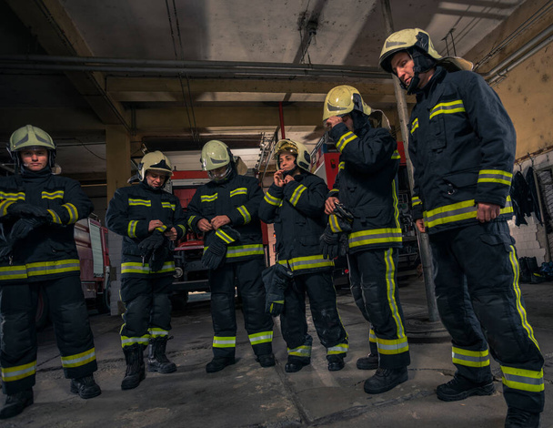 Firemen preparing for emergency service. Firefighters putting on gloves. - Photo, Image
