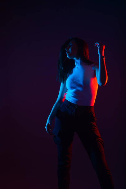 Blue and red light portrait of a female model on a black background with high contrast - Фото, зображення