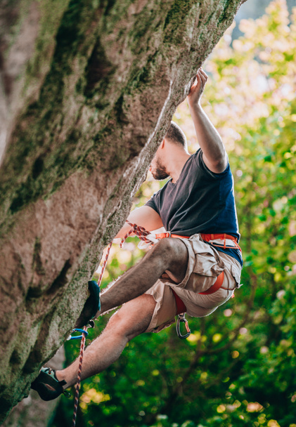 Valiente y confiado escalador de roca hace un movimiento duro en su derrota de escalada - Foto, imagen