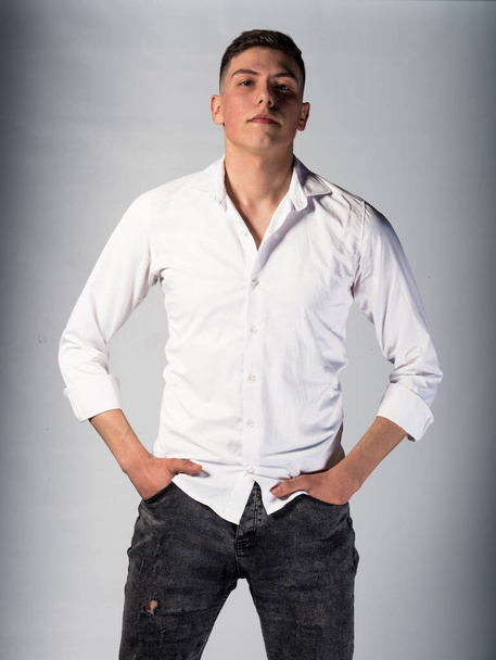Прохолодний молодий чоловік, одягнений у білу сорочку, позує в білій студії
 - Фото, зображення