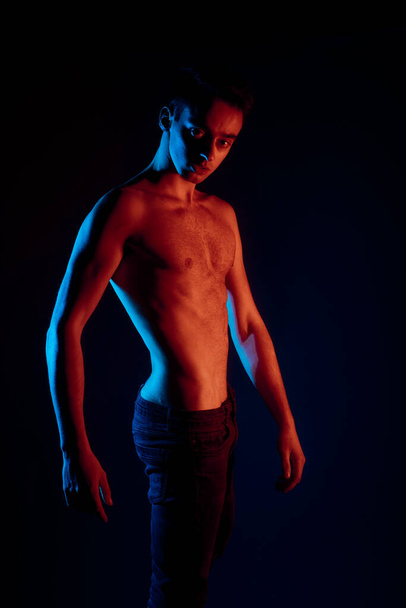 Портрет красивого м'язистого чоловіка, що позує на чорному тлі
 - Фото, зображення