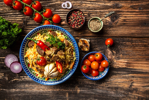 pilaf piatto con ornamento orientale, sfondo in legno, concetto di cucina uzbeka orientale, vista dall'alto, spazio copia. - Foto, immagini