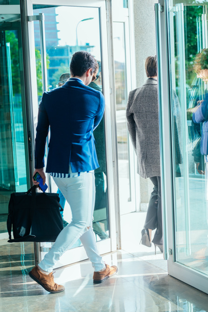 Businesswoman and her male colleague leaving the office building with glass doors. - Photo, image