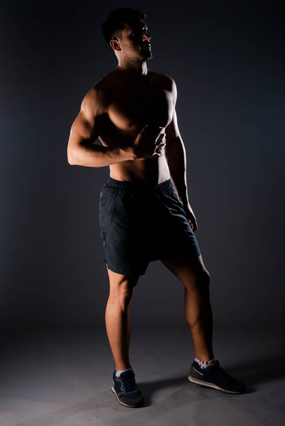 Portrait of a handsome stylish man posing in underwear against black background - Φωτογραφία, εικόνα