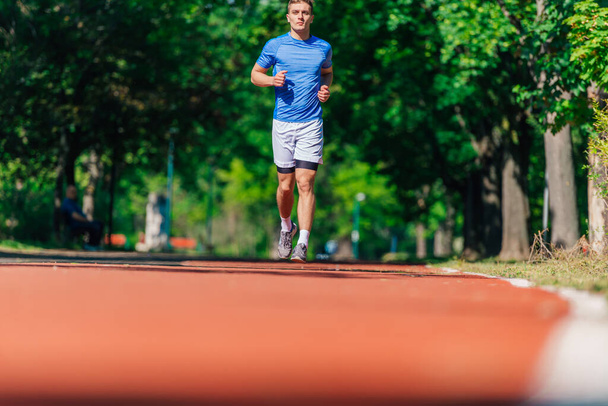 Sterke atletische man joggen op de renbaan - Foto, afbeelding