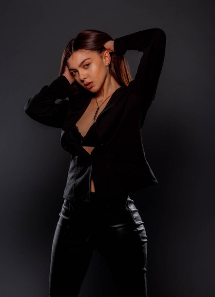 Body shot of a stylish sexy woman posing in black trendy jacket - Фото, изображение