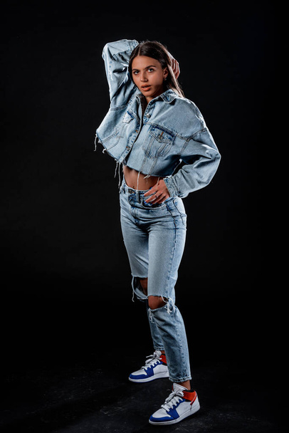 Portrait of a beautiful female model posing in trendy denim jacket and blue jeans - Foto, Bild