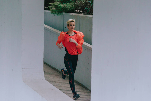 都市部のトレーニングルーチン中に若い健康な女性ランナー - 写真・画像