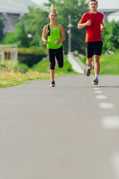 Jovens atletas masculinos e femininos correndo e correndo em uma estrada no parque - Foto, Imagem