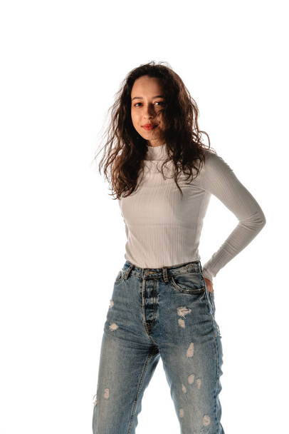 Studio fashion portrait of a modern girl wearing denim pants and white sweater - Photo, Image
