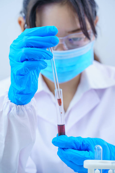 Technician scientist analyzing a blood sample in test tube in laboratory for testing it on COVID, COVID-19, coronavirus virus analysis - Foto, immagini