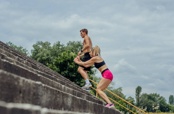 Вид сбоку: активная спортивная пара, прыгающая по лестнице в парке - Фото, изображение