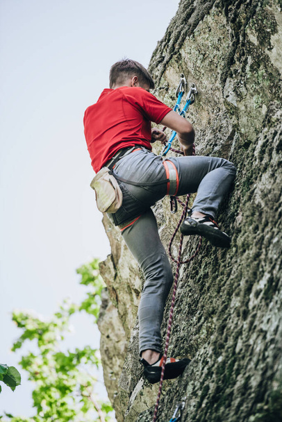 男は完全な登山機器で、安全ベルト、保険とロープでロープに岩を登る - 写真・画像