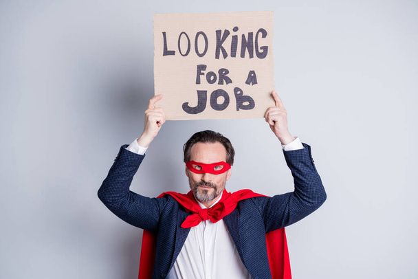 Looking for a job. Photo of stressed mature business guy homeless person career crash super hero costume carton placard seek work wear suit red face mask cloak isolated grey background - 写真・画像