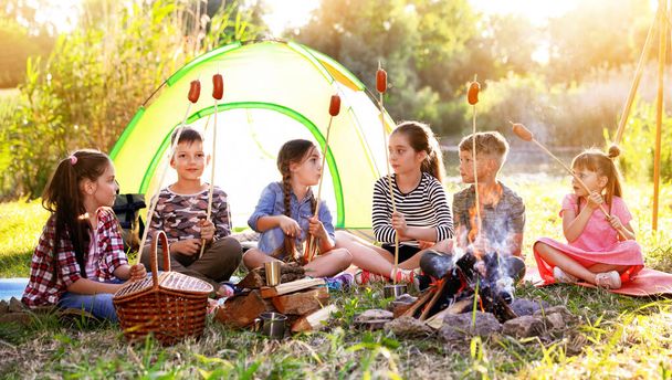 School holidays. Group of happy children frying sausages on bonfire  - Fotografie, Obrázek