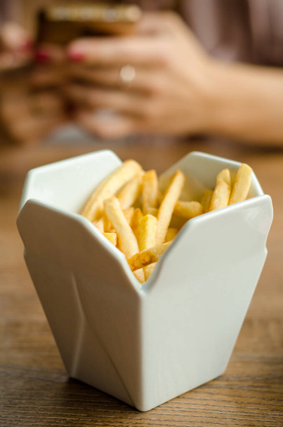 Fritos são servidos no restaurante em caixa de porcelana branca como levar caixa. No fundo de mãos com telefone no almoço - Foto, Imagem