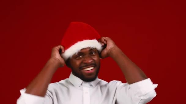 brazilian man wear santa claus headwear isolated over red color background dancing - Záběry, video