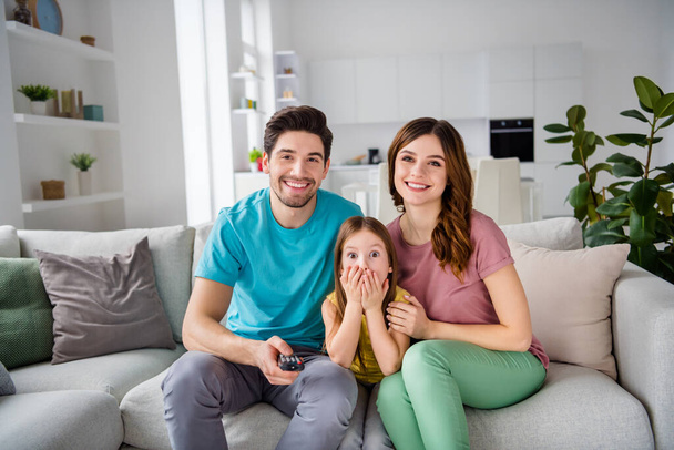 Photo of three people mom dad little kid girl sit comfort couch switch channel remote control have rest watch tv in house indoors - Fotografie, Obrázek