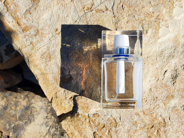 Flacon de parfum rectangulaire en verre sur pierre / roche - Photo, image