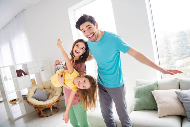 Photo of positive cheerful three people family play game mommy hold little kid girl imagine she fly daddy enjoy rest relax in house indoors - Φωτογραφία, εικόνα