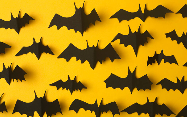 Halloween background. Black bats cut from paper on a yellow background. Halloween decor and decorations for the holiday, copy space. - Valokuva, kuva