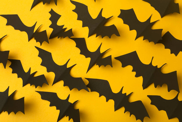 Halloween background. Black bats cut from paper on a yellow background. Halloween decor and decorations for the holiday, copy space. - Foto, imagen