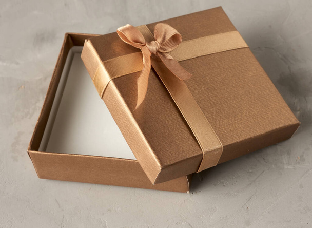 abrir caja de regalo cuadrada dorada sobre fondo gris, vista superior - Foto, imagen