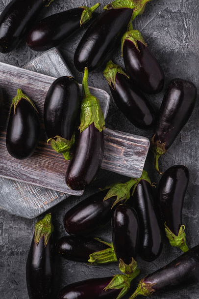 Fresh ripe eggplant on wooden cutting board, stone concrete background, top view - Photo, Image
