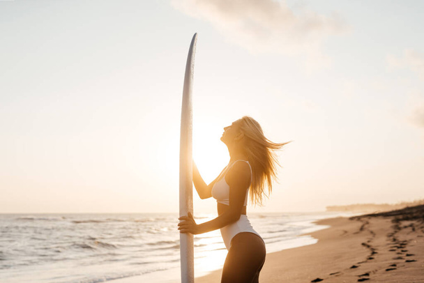 Krásná surfařka na pláži při západu slunce - Fotografie, Obrázek