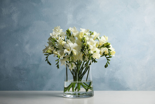 Beautiful freesia flowers in vase on white table - Fotografie, Obrázek