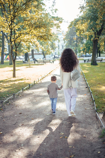 Little boy walks with his mom in autumn park - Foto, imagen