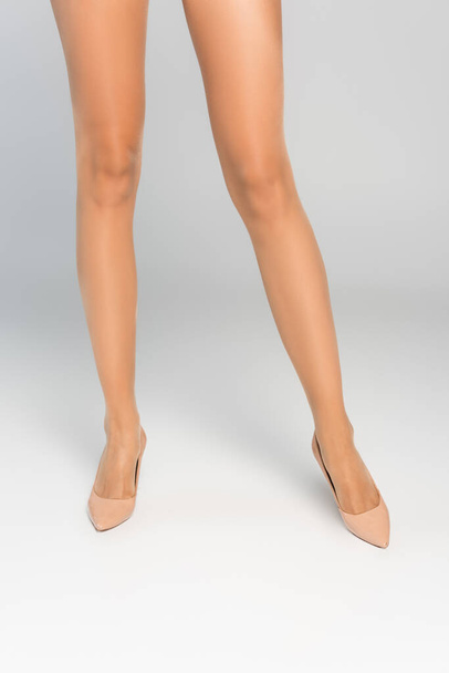 Cropped view of female legs in beige tights and shoes - Foto, Imagem