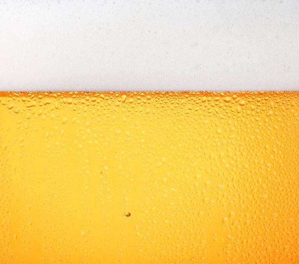 Close up textura de fundo de verter cerveja lager com bolhas e espuma em vidro gelado com gotas, visão lateral de baixo ângulo - Foto, Imagem