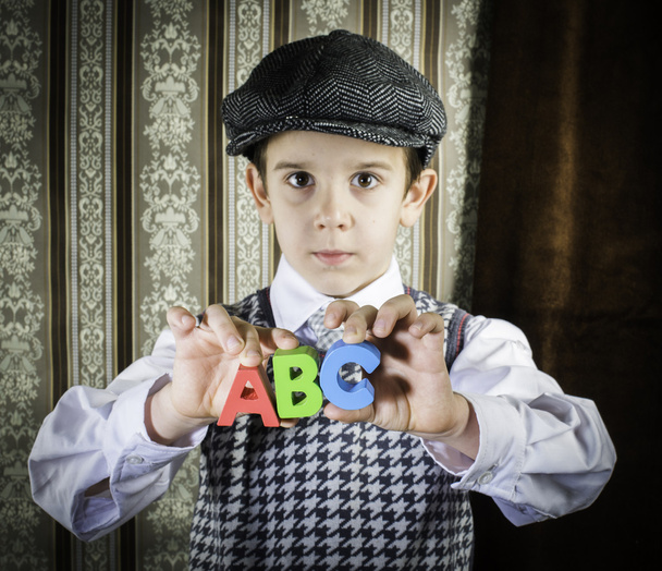 Child in vintage clothes hold letters a b c - Фото, изображение