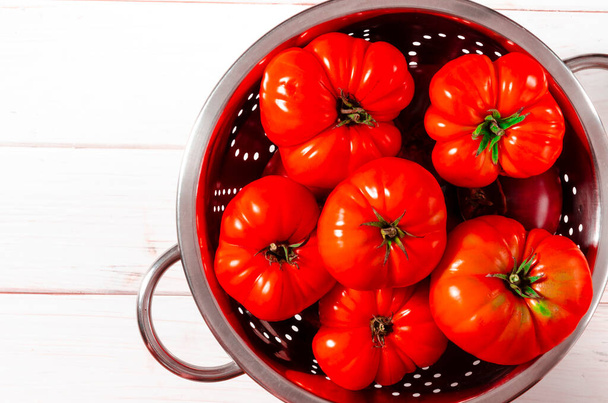 Uma colheita de tomates vermelhos frescos prontos para consumo está em uma mesa de madeira branca - Foto, Imagem