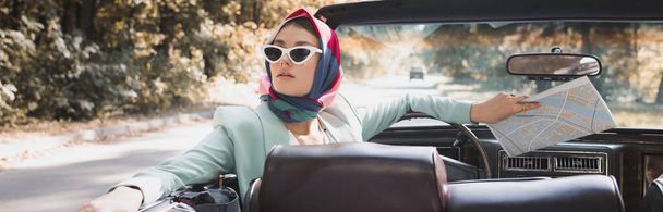Femme élégante avec carte regardant loin en voiture sans toit pendant le voyage sur la route, bannière - Photo, image
