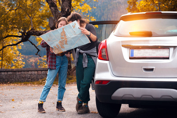 Поездка на машине. Дорожное путешествие - рядом с автомобилем стоит туристическая девушка с картой. Австрия. активный образ жизни - Фото, изображение