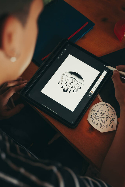 Artista profesional del tatuaje haciendo un boceto en una tableta gráfica en su estudio. - Foto, Imagen
